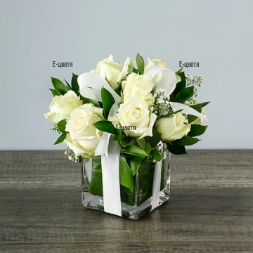 Елегантна аранжировка от бели рози и зеленина в стъклен съд. Нежна и красива тази аранжировка ще краси дома или офиса на любимия човек.