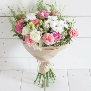 Modern bouquet, arranged with mixed flowers in delicate colours - white and pink, wrapped in fresh greenery and classic gift paper.