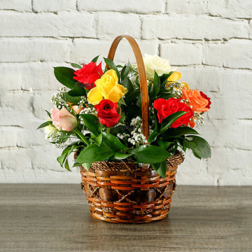 Шарена, весела, "усмихната" кошничка с пъстроцветни рози, нежна, бяла гипсофила и обилна зеленина - един красив, класически аранжимент от цветя.