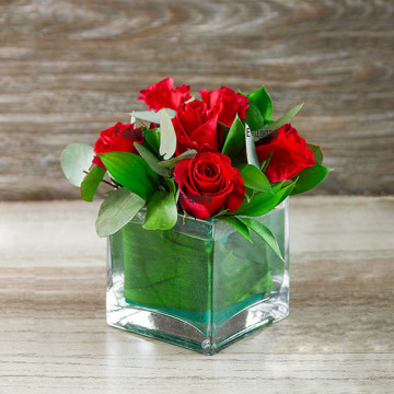 Arrangement with red roses in glass cube