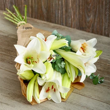 Original, impressive, exotic bouquet of gentle white lilies, arranged with greenery.