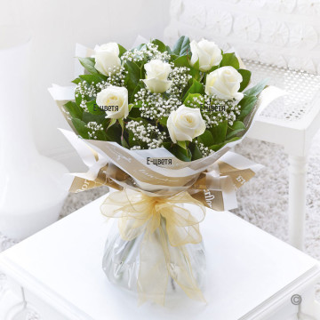 Beautiful bouquet of white roses, a lot of greenery and gypsophila, wrapped in fancy papers
