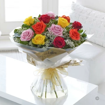 Cheerful, festive bouquet of colourful roses, arranged with delicate white gypsophila, greenery and impressive wrapping.