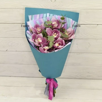 An online order and flower delivery - a bouquet of pink Cymbidium orchids, greenery and wrapping.