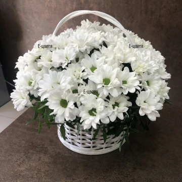 A classic basket with the familiar white chrysanthemums - a fresh combination of flowers and greenery in a rattan basket.