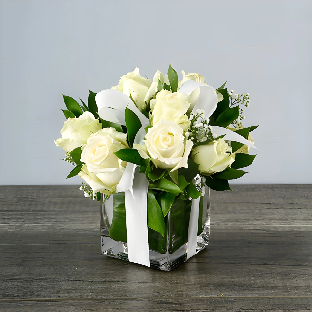 Arrangement of white roses in glass cube.