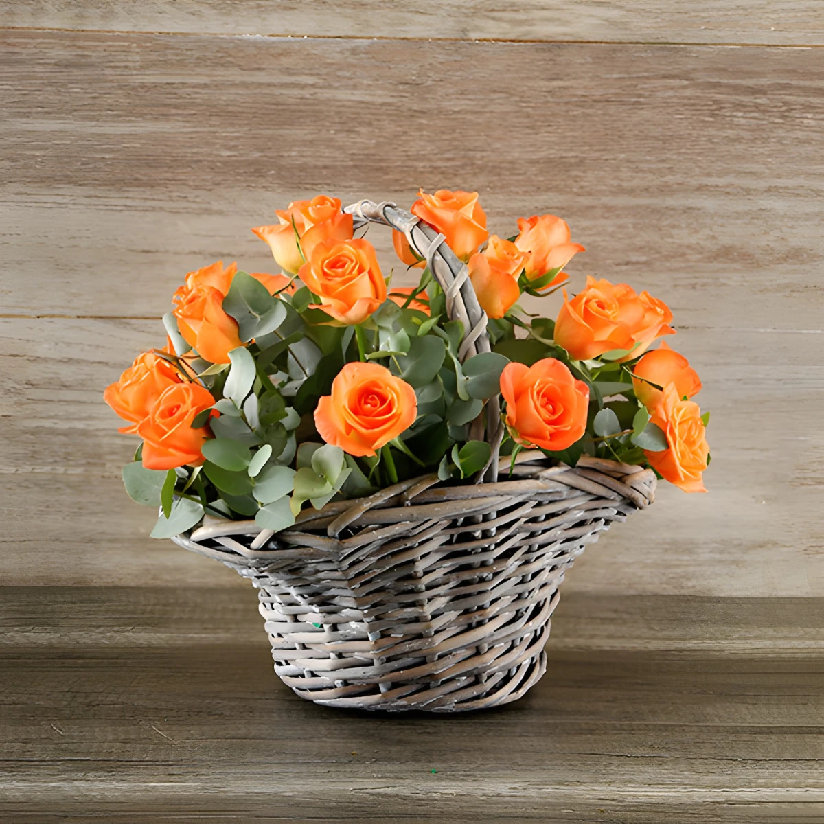 Send a basket with orange roses and greenery.