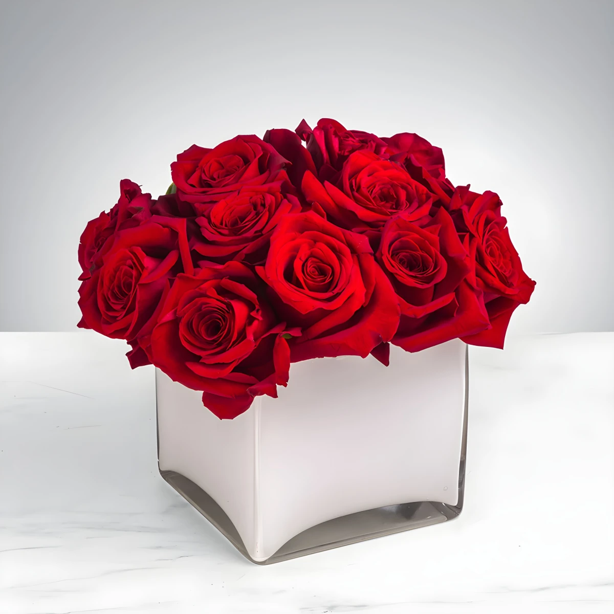 An arrangement of 11 red roses in glass cube.