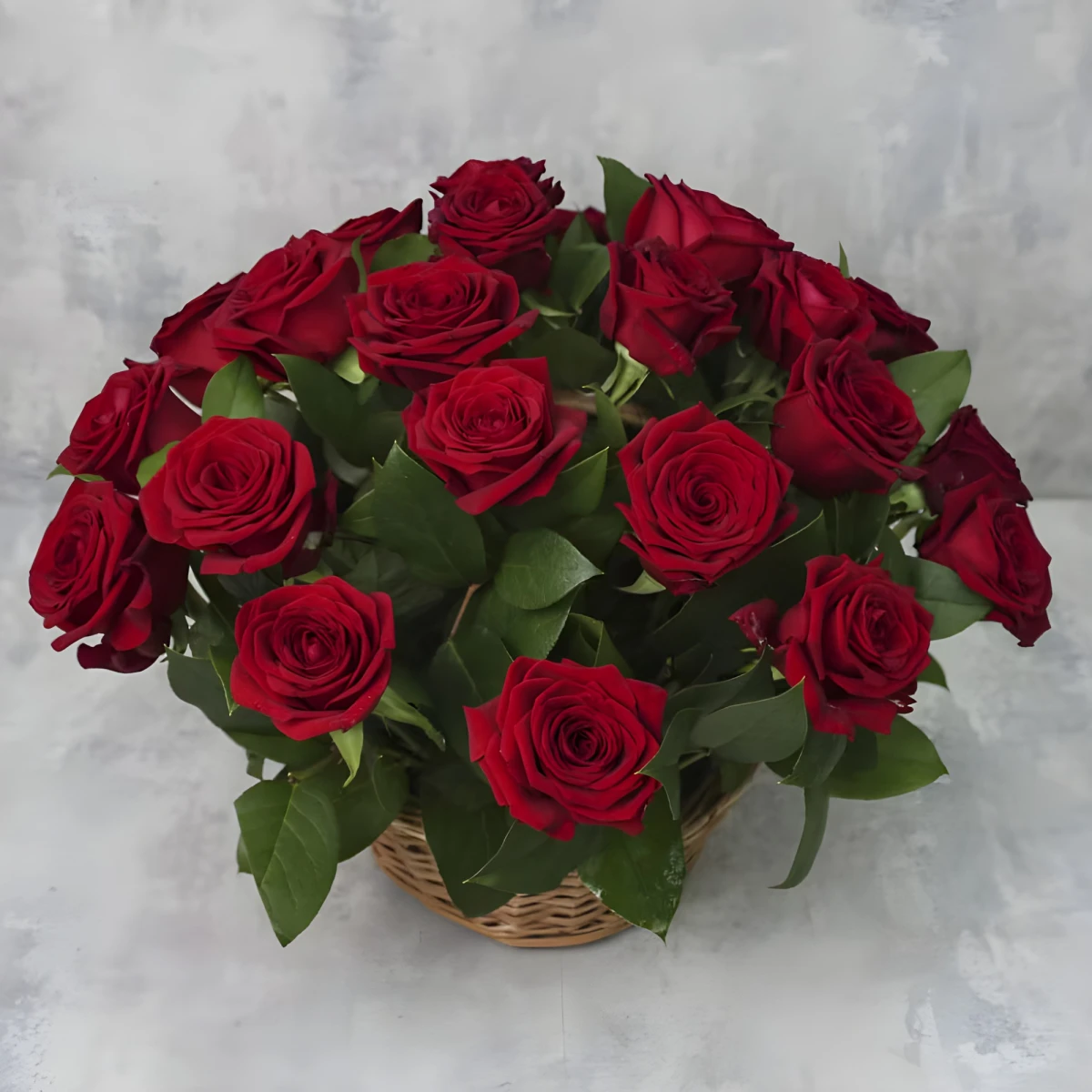 A basket with 21 red roses and greenery.