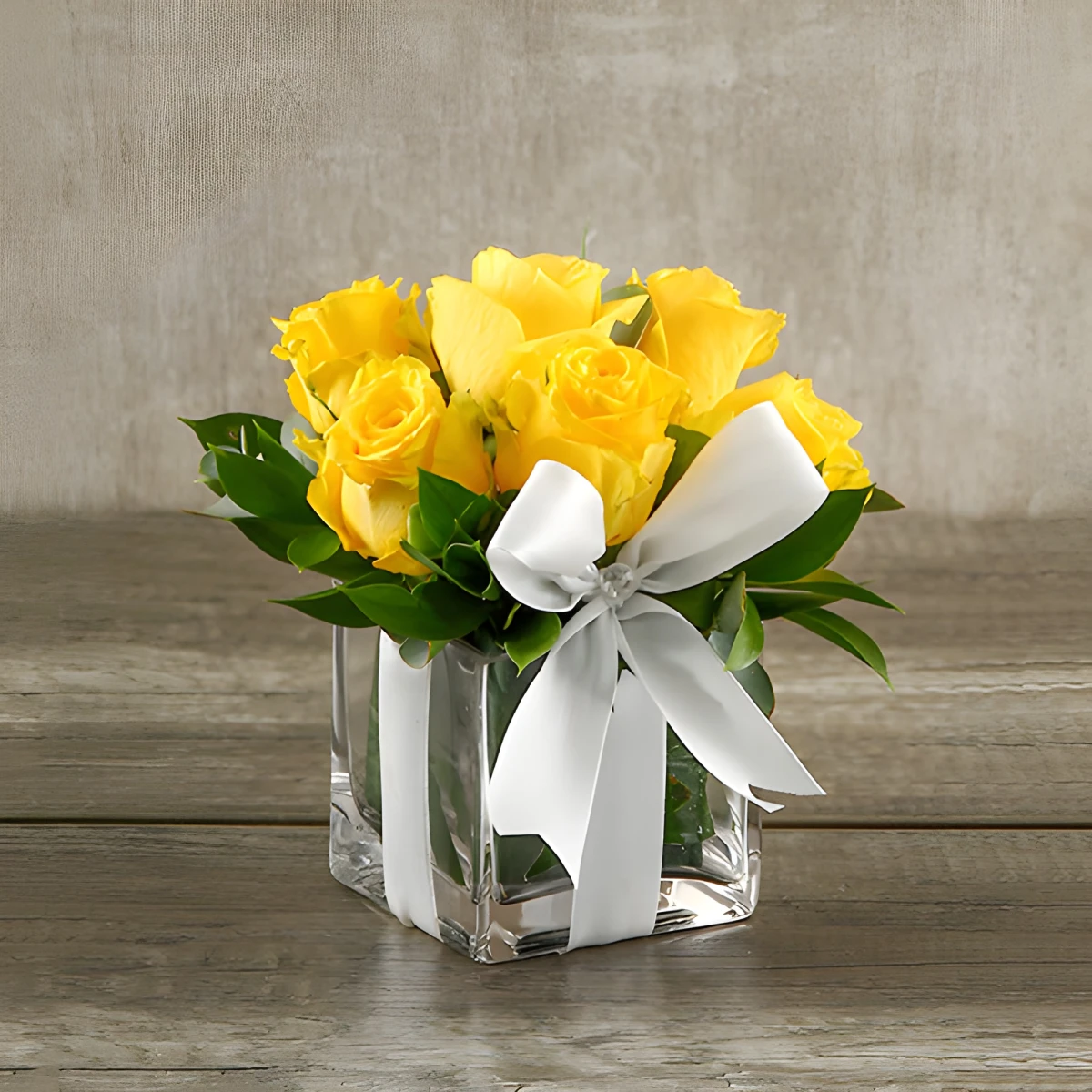 Send an arrangement with roses and greenery in glass cube.
